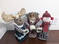 Front view of three fabric dolls: moose, girl, snowman