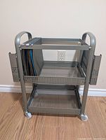Front view of cart showing two shelves, hanging-file frame with folders, side holders, and casters