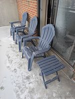 Three matte slate blue Adirondack chairs with matching folding side table on patio