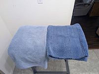 Light blue and medium blue bath mats laid flat side by side