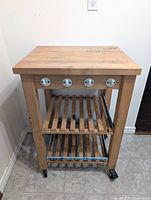 Front view showing butcher block top, pegs, shelves, casters
