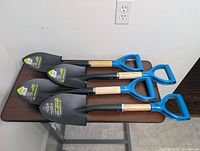 Four identical Yardworks compact shovels showing blades with stickers