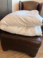 Folded white king size down duvet on ottoman