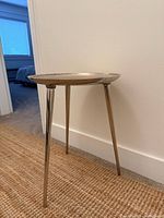 Full view of table against wall showing three legs and round top