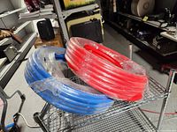 Both red and blue PEX coils wrapped in plastic on shelf