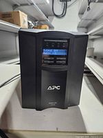 Front view showing APC Smart-UPS 1000 powered on with LCD display