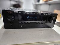 Front view showing Denon 5.2-channel AV receiver, controls, display and feature icons