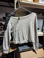 Front view of grey cropped sweater hanging on hanger