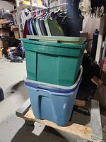 Stacked green and blue storage totes on dolly