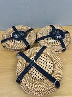 Three bundles of round woven rattan placemats strapped with black ribbon