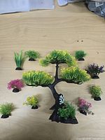 Plastic aquarium tree with assorted small plants spread around on tabletop