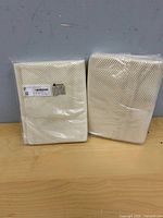 Two sealed off-white mesh rug pads standing upright