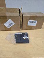 Two cardboard boxes with one sealed black ink cartridge in front