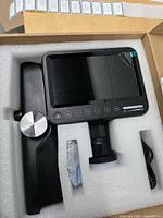 Foam-packed digital microscope showing LCD screen, stand arm and accessories
