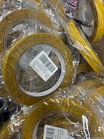 Multiple rolls of yellow double-sided adhesive tape, each wrapped in plastic
