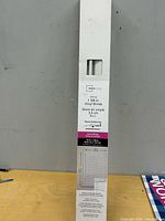 Front of unopened box showing Mainstays white vinyl blinds details