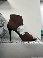 Side profile of one brown stretch fabric stiletto heel on box