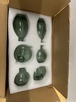Box opened showing six green glass vases seated in foam