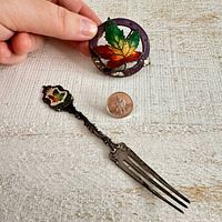 overview of brooch, pin, fork with quarter for scale