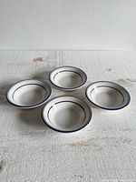 Top view of four identical blue-striped white dip bowls