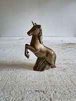 Front and side view of brass unicorn figurine standing on hind legs