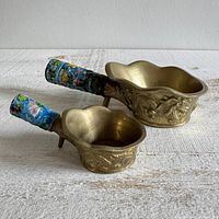 both brass silk irons side by side showing size difference, dragon relief and cloisonné handles