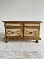 Front view showing gold gilt scroll design and bun feet