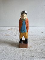 Front view of carved wood sailor figurine on base