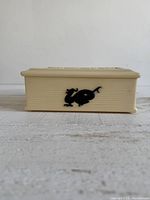 Side view showing cream box with black dragon silhouette