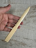 Front view of off-white plastic Payge letter opener held in hand