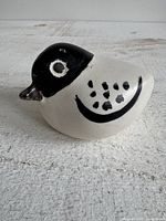 Right side view of ceramic bird showing black head, eye ring, dotted wing and curved line