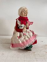 Front view of doll seated in chair holding mug