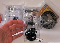 Four sealed HeroClix figures including one visible green mechanical-armed character and three bagged figures