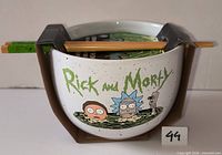 Front view of sealed Rick and Morty ramen bowl with chopsticks in packaging