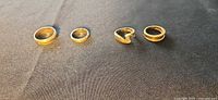 All four 14k gold rings shown on dark fabric background