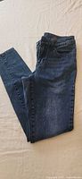 Front view of jeggings folded to show dark wash denim and front pocket details
