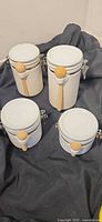 Set of four white porcelain canisters with attached wooden spoons