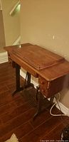 Closed view of Singer wooden folding sewing table on cast iron base