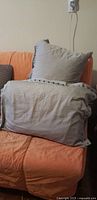 Two light grey bed pillows stacked on sofa