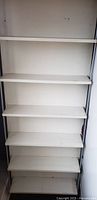 Front view of tall white shelving unit with six shelves