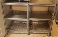 Front view of both stainless carts showing shelves and wheels