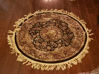 Round oriental-style rug with fringe displayed on hardwood floor