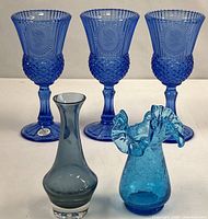 Five blue glass pieces grouped: three goblets, crackle vase, bud vase