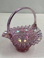 Full view of iridescent pink carnival glass basket showing handle and ruffled rim