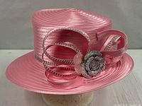 Full view of bright pink ribbon hat with rhinestone bow and brim
