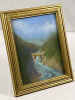 Front view of gold-tone frame with river illustration