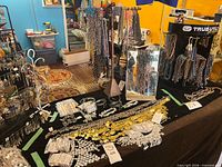 Overview of lot within green tape on tabletop showing coin belts, chain jewellery, packaged parts