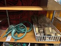 Shelf view showing green metal French horns and basket of brass livestock bells