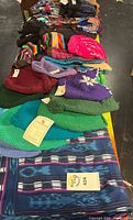 Top view of table showing multiple knit hats, gloves, scarves