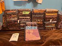 Front view of two large shrink-wrapped stacks of assorted cotton wallets with three sample wallets displayed